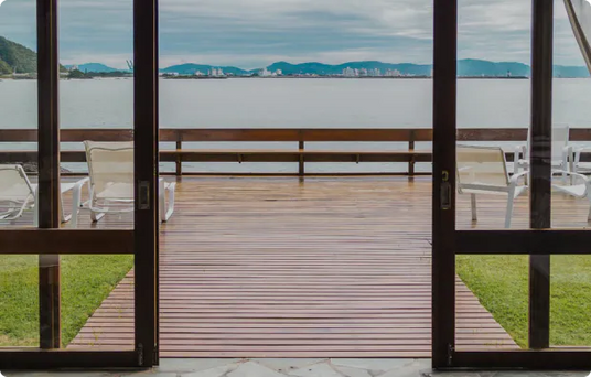Gemütliche Terrasse mit Blick aufs Meer, elegant eingerichtetes Zimmer mit Vorhängen und Sitzgelegenheiten