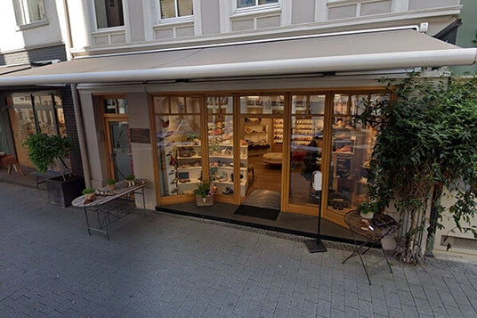 Außenansicht eines charmanten Schuhladens mit großen Glasscheiben und einladender Dekoration in einer belebten Straße