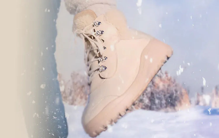 Ein Paar Lammfellschuhe im Schnee, geeignet für Damen und Herren, mit winterlicher Landschaft im Hintergrund