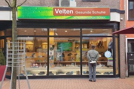 Ein Mann steht vor dem Schaufenster von Velten Gesunde Schuhe, einem Geschäft für orthopädische Schuhtechnik.